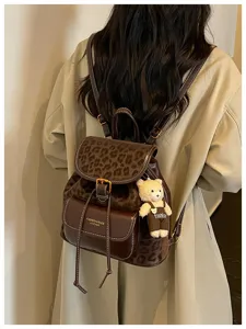 Vue détaillée du sac à dos rétro avec motif léopard et joli pendentif d'ours brun.