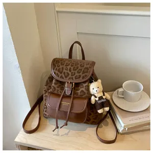 Détail du sac à dos rétro léopard marron avec pendentif ours mignon sur table en bois.