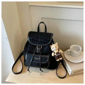 Vue détaillée du sac à dos noir motif léopard avec charm ours mignon et poche frontale.