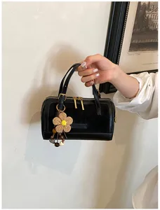Chic black pillow handbag detail, stylish shoulder crossbody bag with cute straw flower charm.