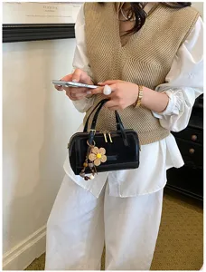 Detailed view of the stylish black pillow shoulder bag with metal zippers and flower charm.