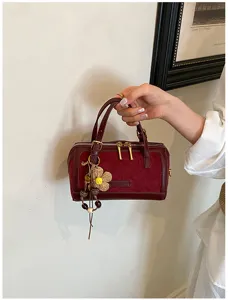 Detailed view of the dark red suede pillow bag with chic hanging charm and durable hardware.