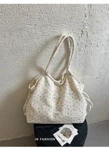 Vista dettagliata di una borsa beige plissettata con spallacci eleganti e casual.