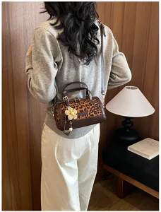 Detailed view of the stylish leopard print shoulder pillow bag worn by a model indoors.