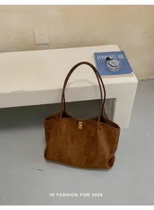 Detailed view of a stylish brown suede tote bag, casual minimalist shoulder bag with metal lock.
