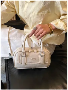 Détail de sac à main rétro chic avec poignée supérieure montrant une texture cuir.