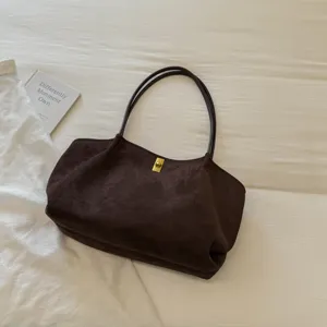 Detailed shot of dark brown suede shoulder bag with gold turn-lock and double straps.