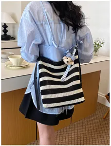 Black and white striped woven tote bag detail showing casual commuting style and cute bear pendant.