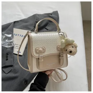 Elegante bolso cruzado tejido de color beige para mujer con lindo osito colgante y buen diseño.