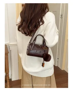 Vue de détail d'un sac bandoulière boston marron rétro avec pompon pelucheux.