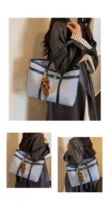 Detailed view of the grey blue commuting tote bag with chic bear pendant and leather trim.