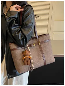 Detailed view of women's retro tweed tote bag with leather trim and cute bear pendant.