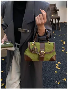 Λεπτομέρεια από κοντά vintage πράσινης τσάντας σουέτ με καφέ δερμάτινη επένδυση και αγκράφα.
