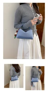 Stylish blue pillow shoulder bag with beaded charm detail, perfect for daily outfits.