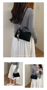 Detailed shot of the retro black shoulder pillow bag with wooden bead pendant on model.