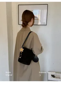 Minimalist black bucket bag for women, chic single shoulder bag with cute flower charm.