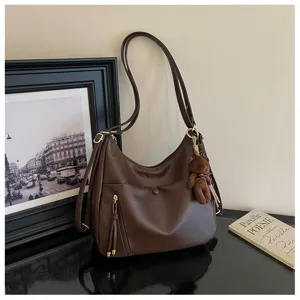 Vintage bruine dames schoudertas met grote capaciteit en schattige berenhanger voor dagelijks.