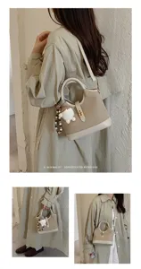 Detail view of stylish retro canvas shoulder bag with cute plush pendant and gold lock.