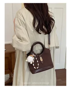Women leather commuter shoulder crossbody bag with cute charm and metal lock closure detail.