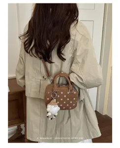Detail shot of the retro polka dot bowling bag with cute doll charm, stylish crossbody style.