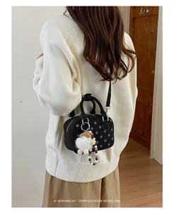 Detailed view of the stylish black polka dot bowling bag with cute plush doll charm.