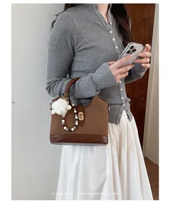 Detailed view of stylish retro top handle shoulder bag with pearl and plush ball charm.