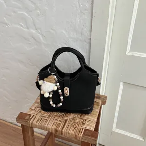 Handbag detail view, elegant black design with metal lock and cute charm for daily commute.