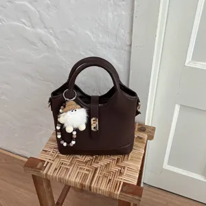 Brown commuter shoulder bag detail shot, minimalist style handbag with cute plush keychain charm.