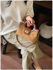 Elegante borsa a mano in pelle scamosciata marrone con chiusura a torsione e tracolla.