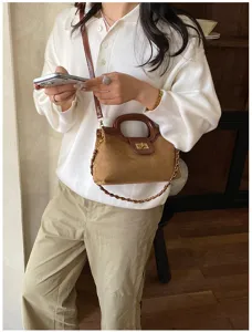 Primo piano dettagliato della borsa in camoscio marrone vintage con chiusura e catena.