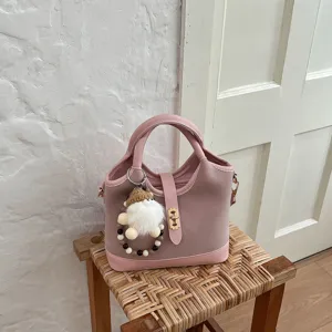 Pink bucket handbag with cute plush doll charm, elegant shoulder crossbody bag detail view.