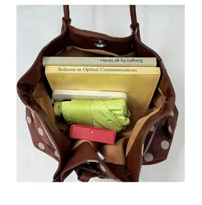 Vista dettagliata della grande borsa marrone a pois che mostra lo spazio interno con libri.