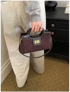 Elegante borsa in camoscio marrone scuro con dettagli verniciati e chiusura dorata chic.