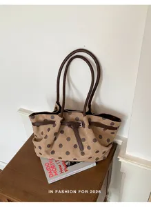 Vista dettagliata della grande borsa tote in tela a pois con manici e cinturino in pelle.