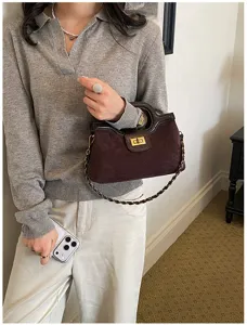 Primo piano dettagliato della borsa in pelle scamosciata marrone scuro con tracolla a catena.