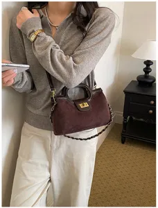Borsa a tracolla chic in camoscio marrone con chiusura a torsione dorata e dettaglio di catena.