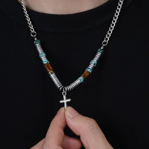 Vue détaillée du collier pendentif croix en métal avec perles turquoise et spirales pour femmes.