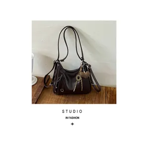 Detail shot of the dark brown leather shoulder bag, featuring soft texture and stylish charm.
