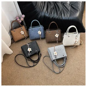 Vista de detalle del bolso de mano para mujer elegante con varios colores y colgante floral.