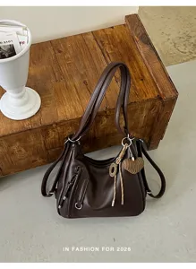 Detailed view of the dark brown leather shoulder bag with chic front zip pockets.