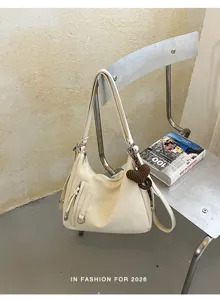 Minimalist off-white shoulder bag with chic front pocket and modern metal chair display.