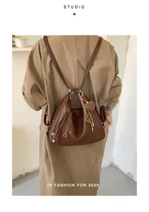 Detailed view of brown leather backpack with heart charm, stylish commuter shoulder bag.