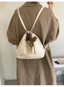 Detailed view of white soft leather convertible backpack with cute heart knit charm.