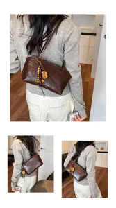 Detailansicht einer stilvollen braunen Leder-Unterarmtasche für Damen mit Holz-Kleeblatt-Anhänger.