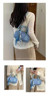 Detailed view of a light blue denim Boston handbag with pearl star charm, worn by a model.