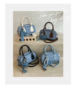 Close-up detail of stylish denim Boston handbag with contrast handles and charming charms.
