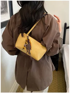 Detailansicht der minimalistischen gelben Schultertasche mit Holz-Kleeblatt-Anhänger.