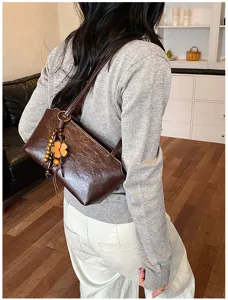 Detailansicht der eleganten braunen Leder Schultertasche mit Holzperlen Kleeblatt Anhänger.