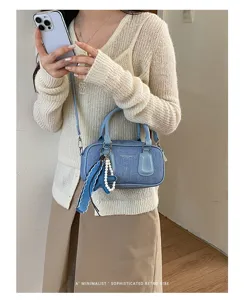 Chic blue denim boston handbag featuring retro design, top handles, and stylish charm accessory.
