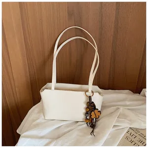 Detailaufnahme einer minimalistischen weißen Handtasche mit Holzperlen-Kleeblatt-Anhänger.